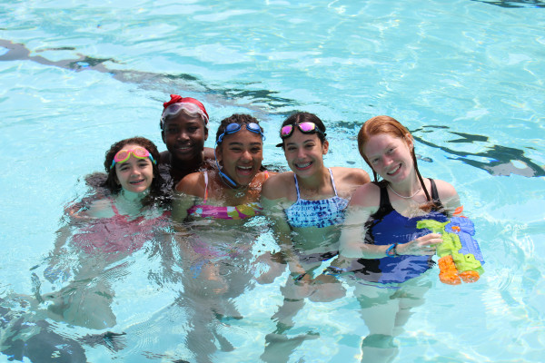 Five campers smiling together in the camp swimming pool