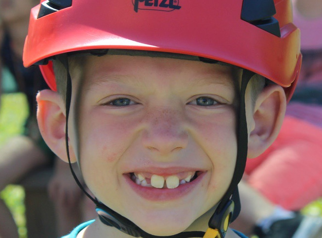 Smiling young camper in a red climbing helmet